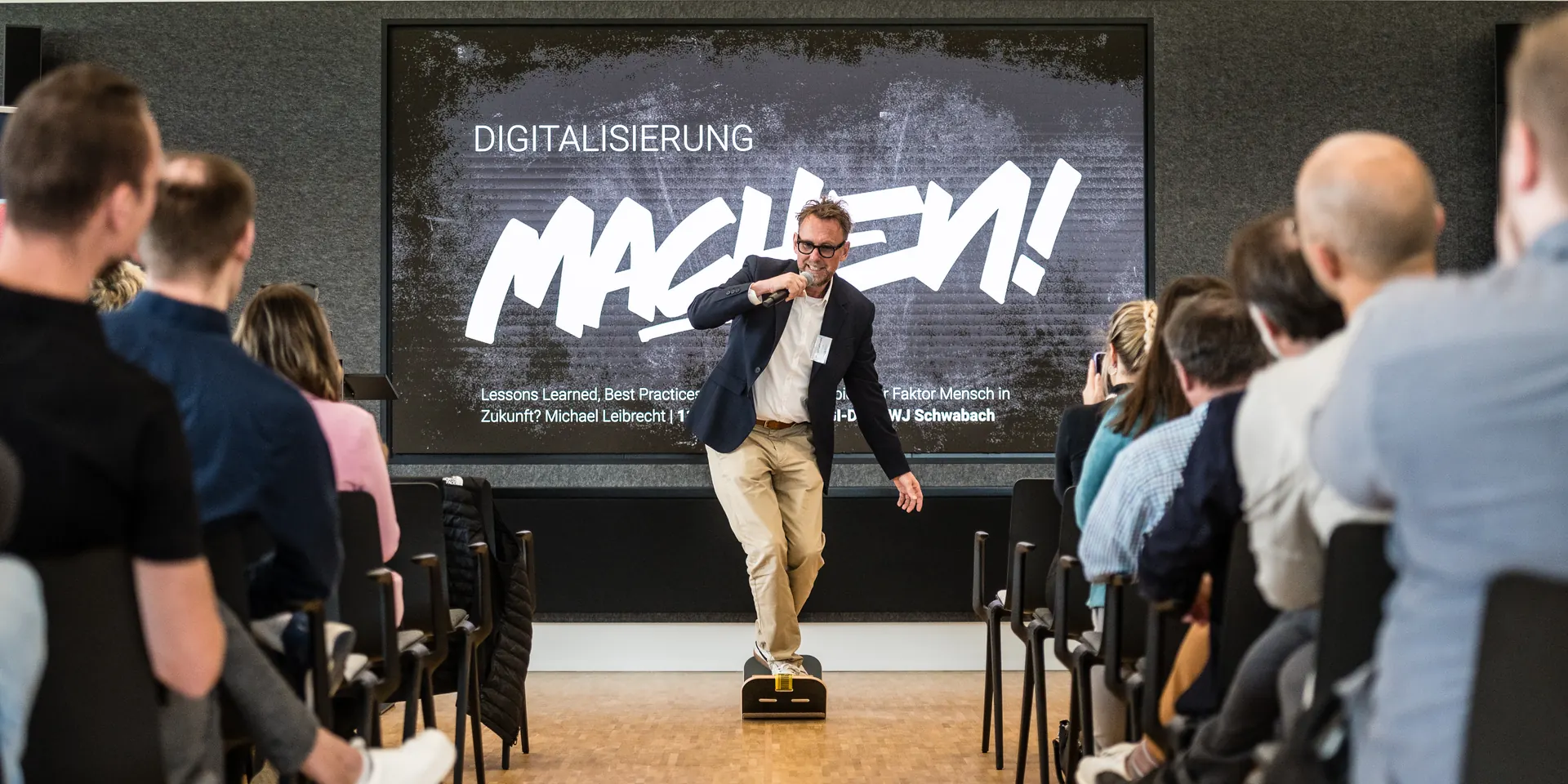 Michael Leibrecht bei einem Vortrag, auf der Leinwand steht Digitalisierung machen